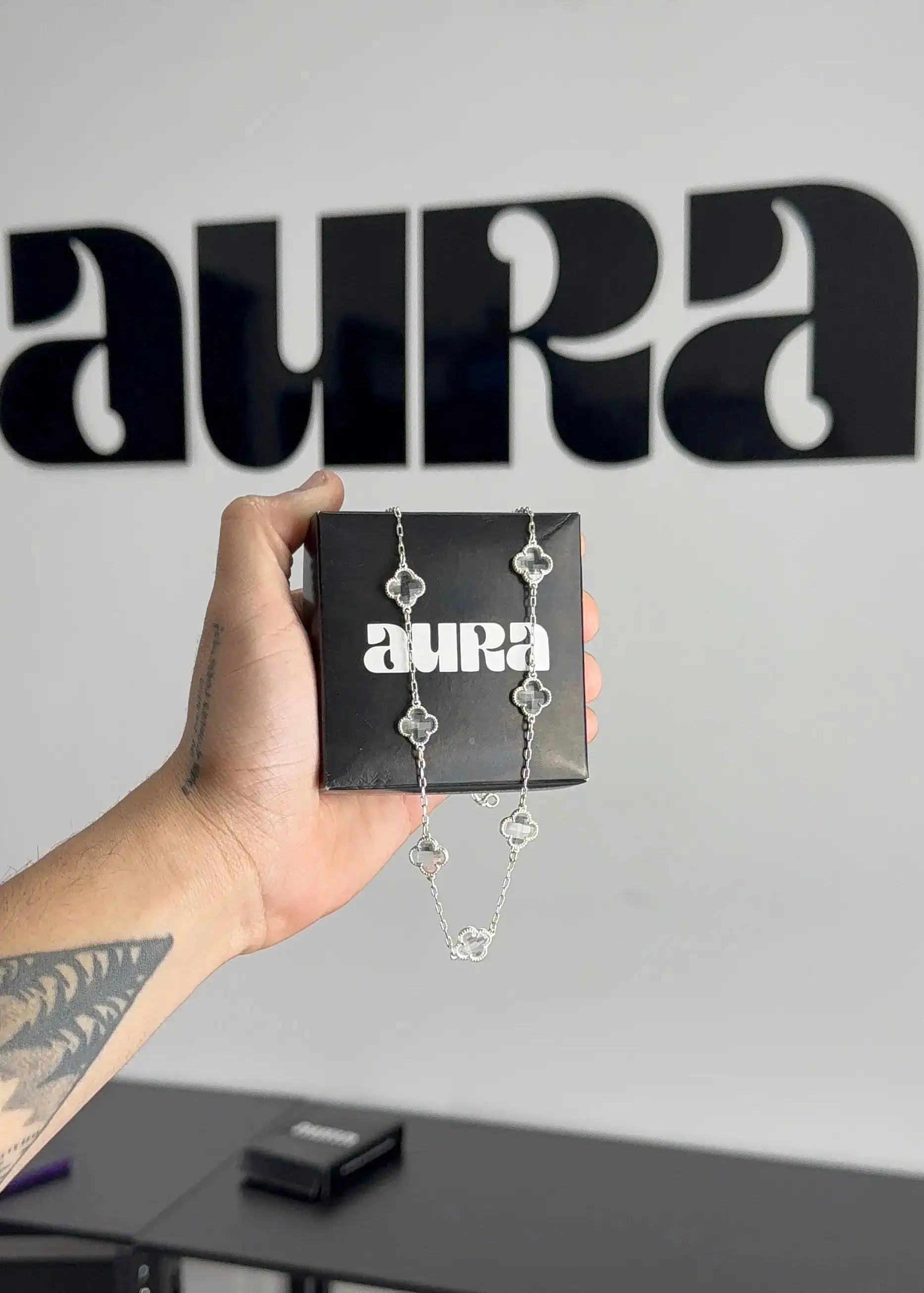 Colar em prata 925 com detalhes em forma de flor, apresentado em caixa preta com logotipo Aura.